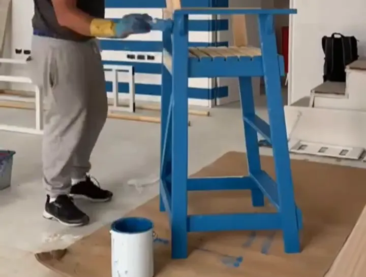 Prestador de servicios pintando un banco de madera de color azul