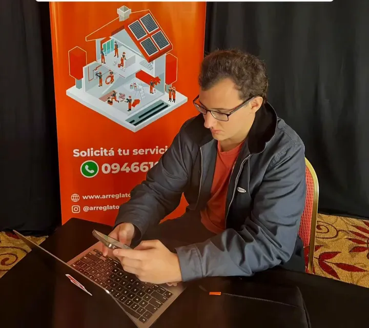 Integrante del equipo con la notebook junto a un banner de ArreglaTodo